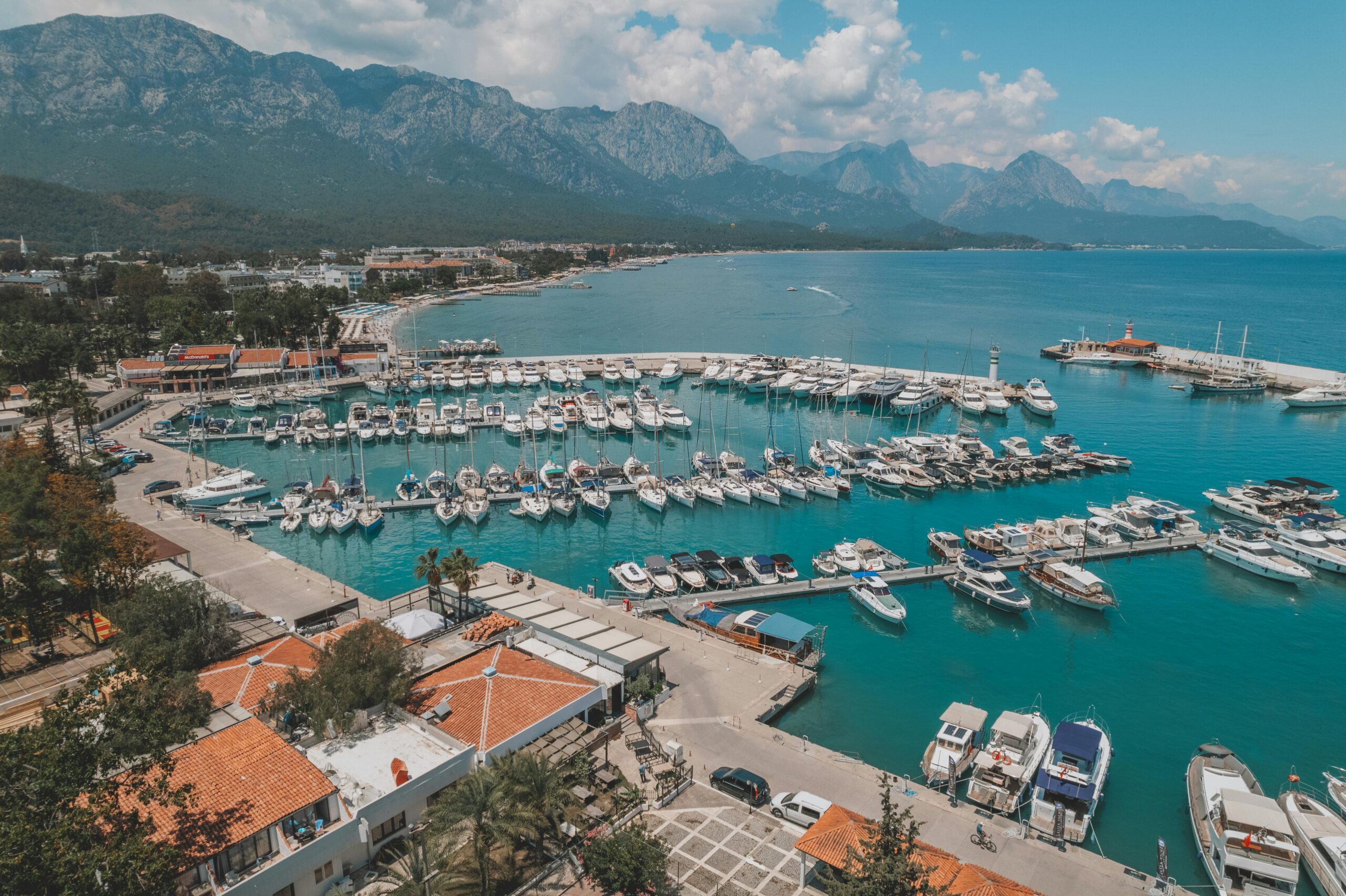 Stunning aerial view of Kemer marina with yachts and mountains in Antalya, Türkiye.