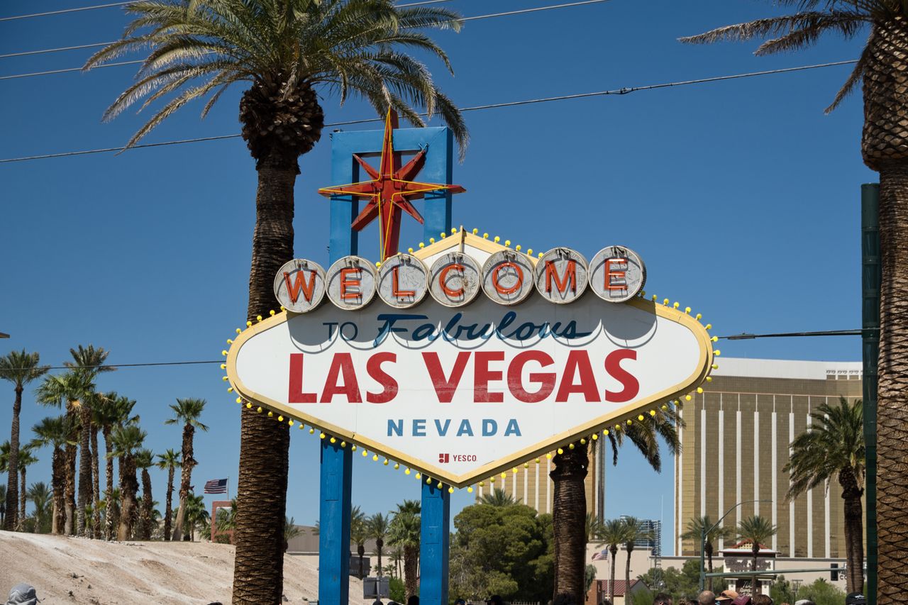 Famous Las Vegas sign against a clear blue sky with palm trees symbolizing vibrant city life.